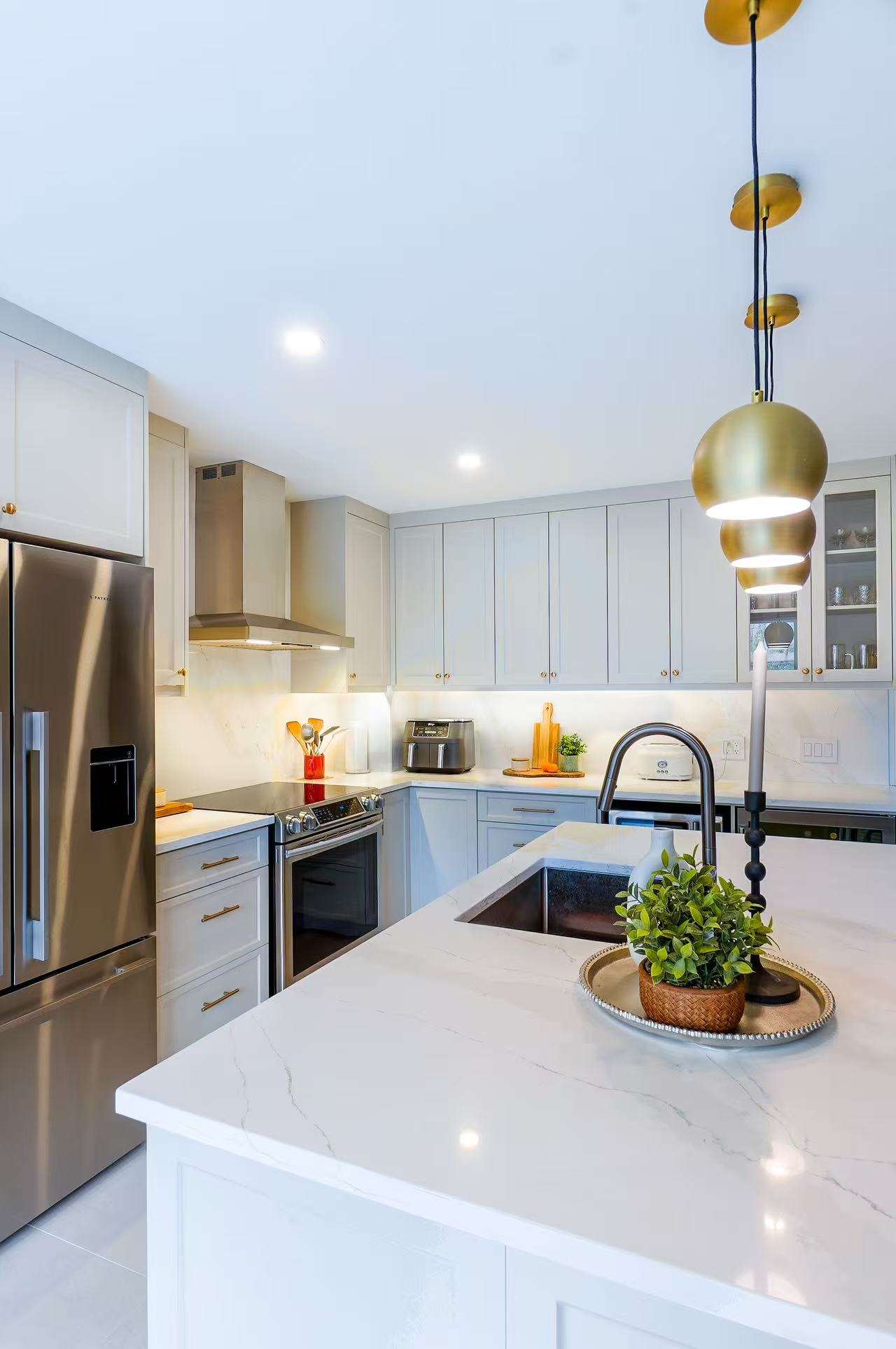 White kitchen island with brass pendant lights